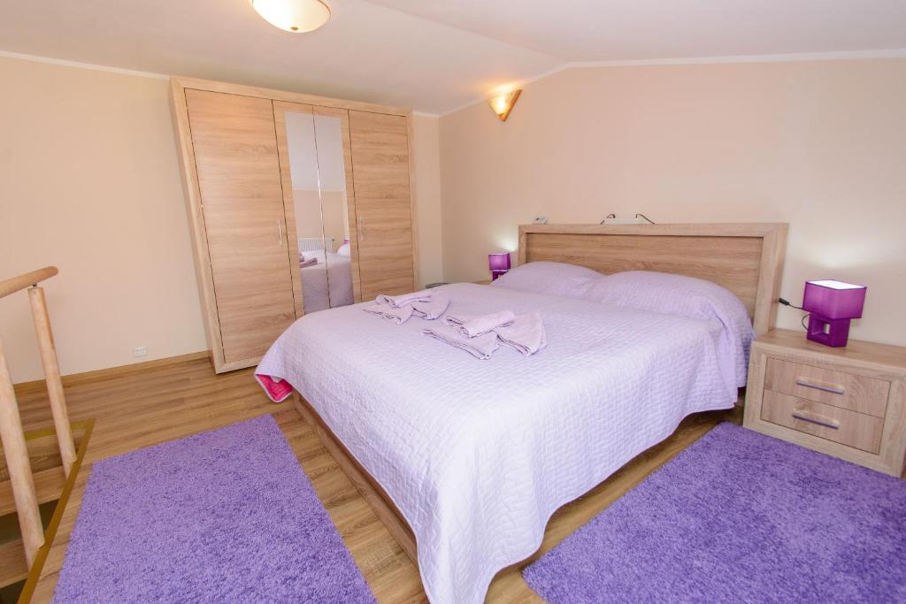 a bedroom with a large white bed with purple rugs at Apartament Alpha in Bistriţa