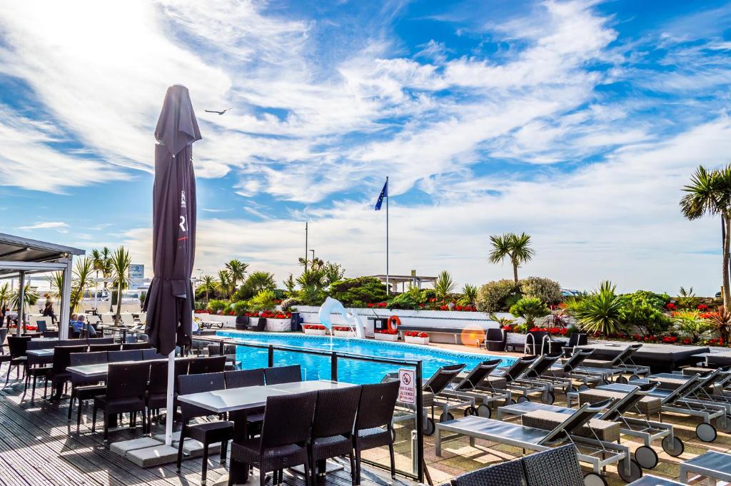a pool with tables and chairs and a umbrella at Cumberland Hotel - OCEANA COLLECTION in Bournemouth