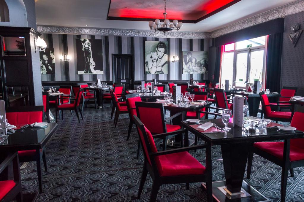 a dining room with tables and red chairs at Cumberland Hotel - OCEANA COLLECTION in Bournemouth