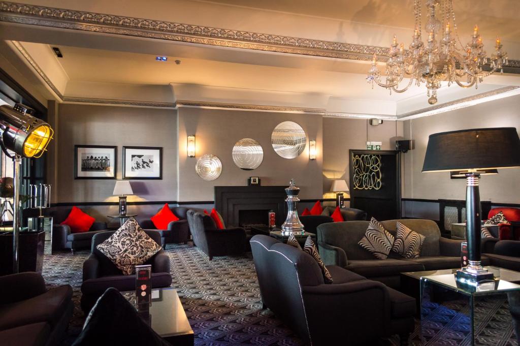 a living room with couches and a chandelier at Cumberland Hotel - OCEANA COLLECTION in Bournemouth