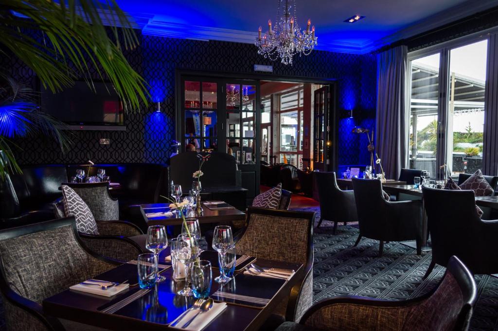 a restaurant with tables and chairs and a chandelier at Cumberland Hotel - OCEANA COLLECTION in Bournemouth