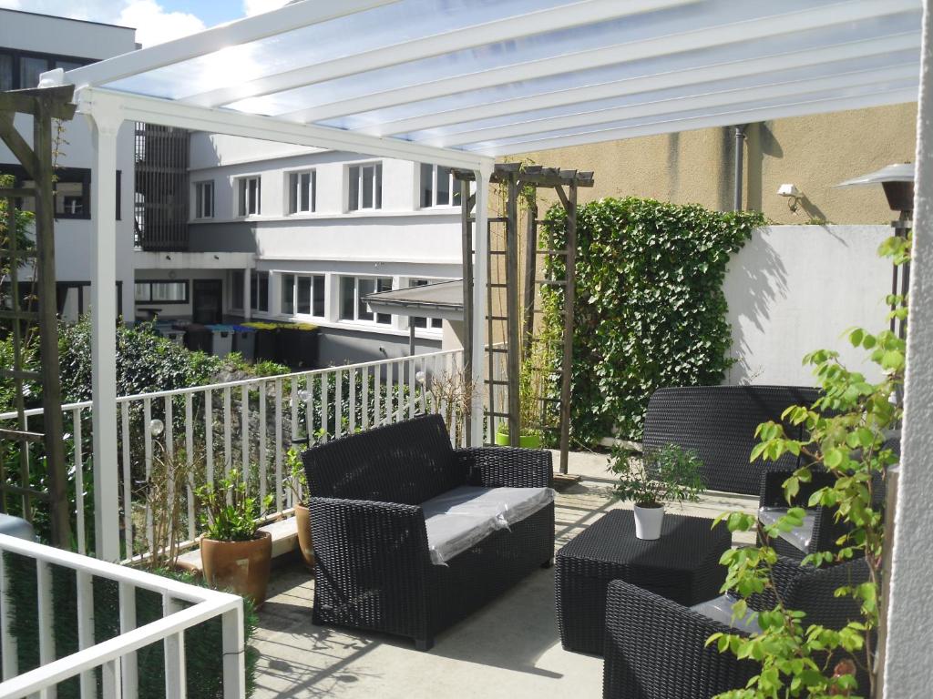 un patio con una pérgola blanca y una silla en Gites de Daumesnil Appartement La Loob en Morlaix