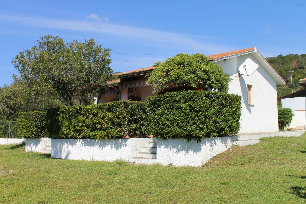 a white house with green bushes in front of it at Lacona Mare by HelloElba in Lacona