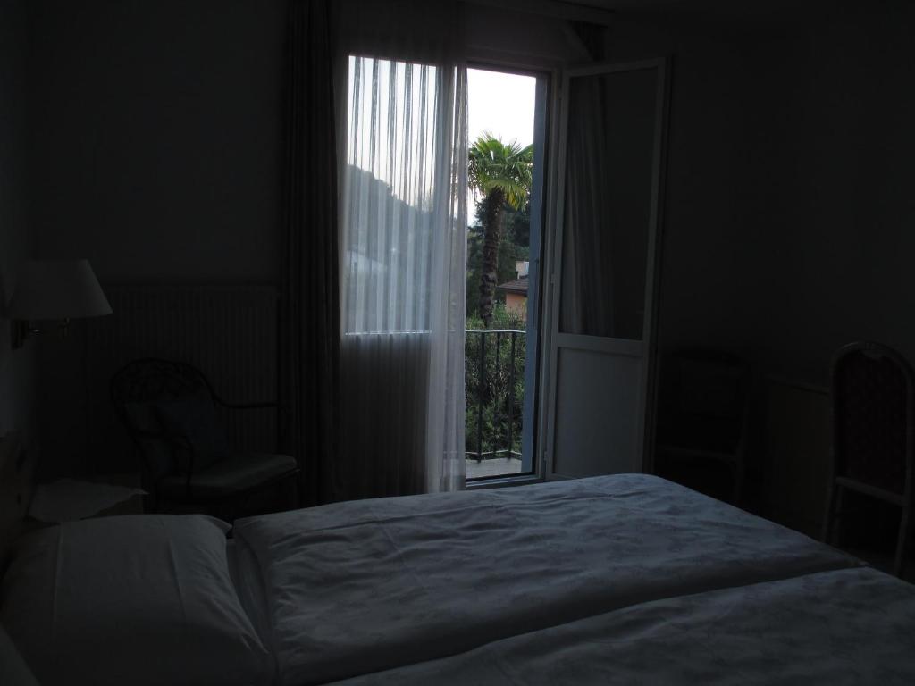 a bedroom with a bed and a large window at Hotel Arcadia in Ascona