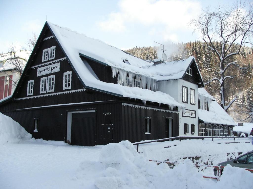 ペツ・ポト・スニェシュコウにあるHospoda na Peciの屋根に雪が積もった黒納屋