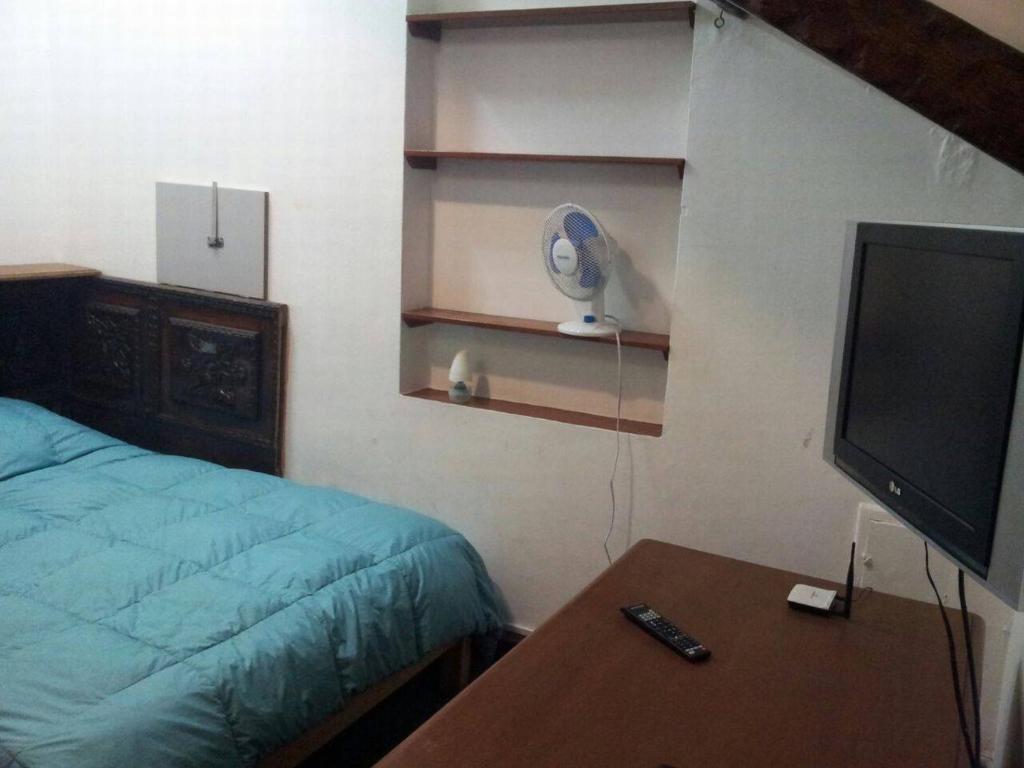 1 dormitorio con 1 cama, TV y mesa en La Quinta Alcanfores, en Lima