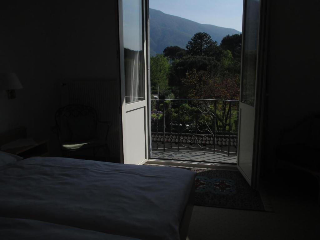 a bedroom with a bed and a view of a balcony at Hotel Arcadia in Ascona