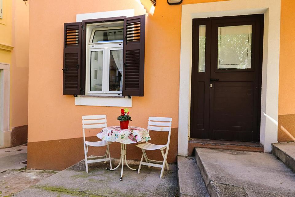 stół i krzesła siedzące przed budynkiem z drzwiami w obiekcie Altstadt w mieście Lovran