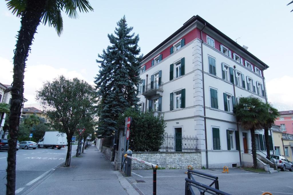 a white building with a tree in front of it at White Residence Apartment in Riva del Garda