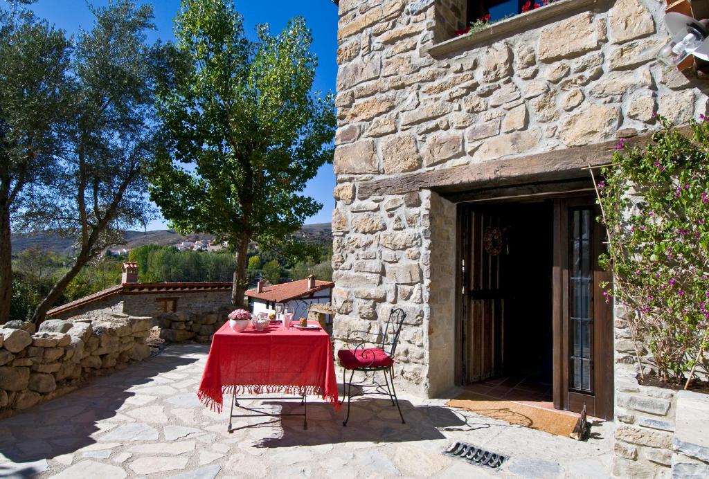 uma mesa com uma toalha de mesa vermelha sentada em frente a um edifício em Casa Tia Upe em San Román de Cameros