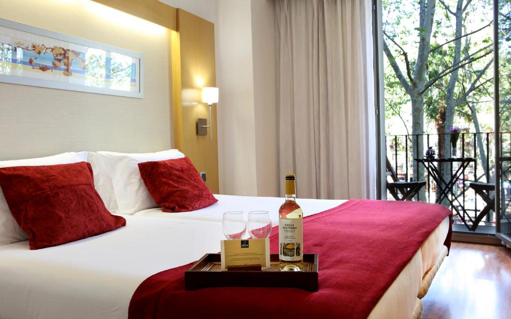 - une bouteille de vin et des verres sur le lit dans l'établissement Abba Rambla Hotel, à Barcelone