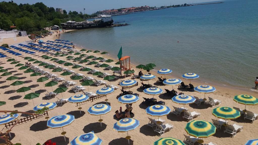 a beach with blue and white umbrellas and the water at Apartment Crystal Beach in Nesebar