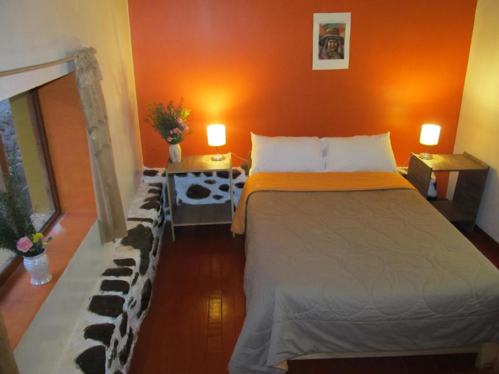 1 dormitorio con 1 cama grande y paredes de color naranja en Killari Hostal Ollantaytambo, en Ollantaytambo