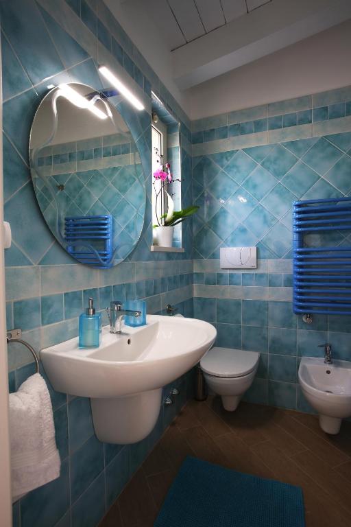 W wyłożonej niebieskimi kafelkami łazience znajduje się umywalka i toaleta. w obiekcie B&B Casa Rubis w mieście Ruvo di Puglia