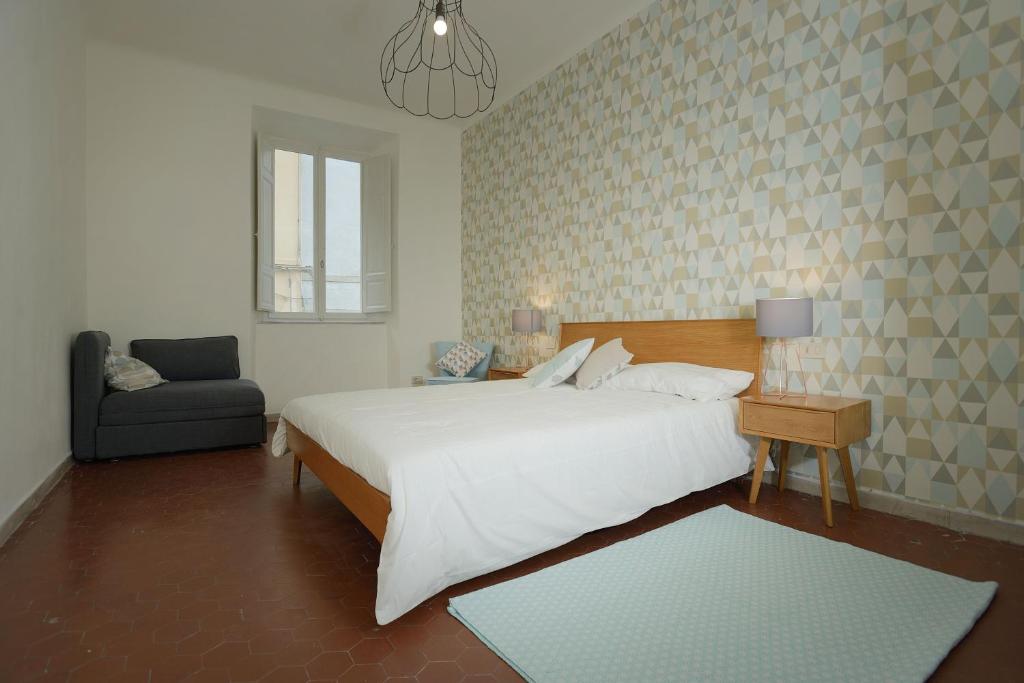 a bedroom with a large white bed and a chair at Le camere di Sementis in Pietrasanta