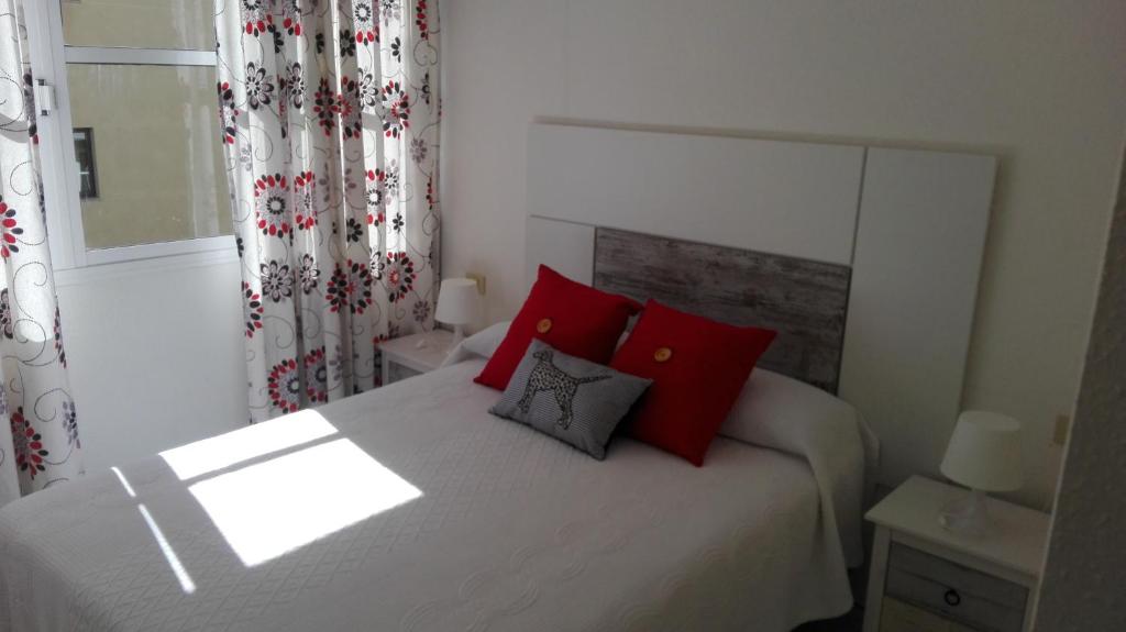 um quarto com uma cama com almofadas vermelhas e uma janela em Montaña Roja em El Médano