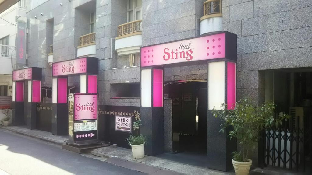 a building with pink and white signs on it at Hotel Sting in Tokyo