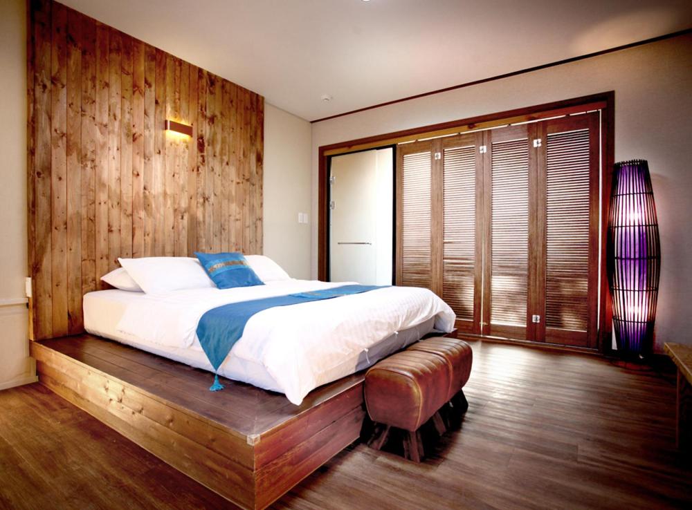 a bedroom with a large bed and a wooden wall at Thai Story in Seogwipo