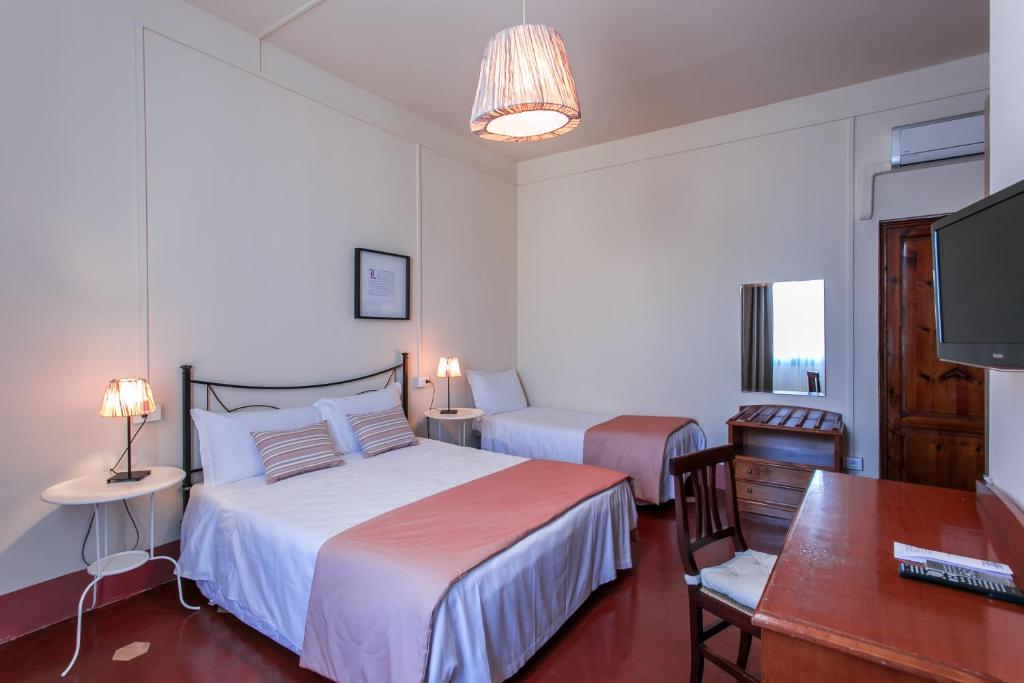 a hotel room with two beds and a desk and a television at Hotel d'Azeglio Firenze in Florence