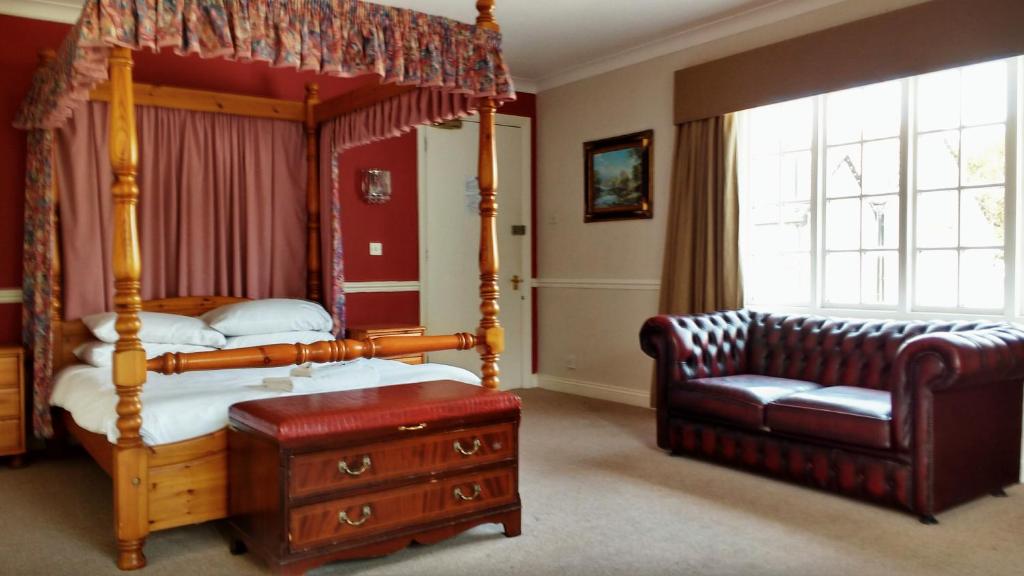 a bedroom with a canopy bed and a couch at The Bell House in Sutton Benger