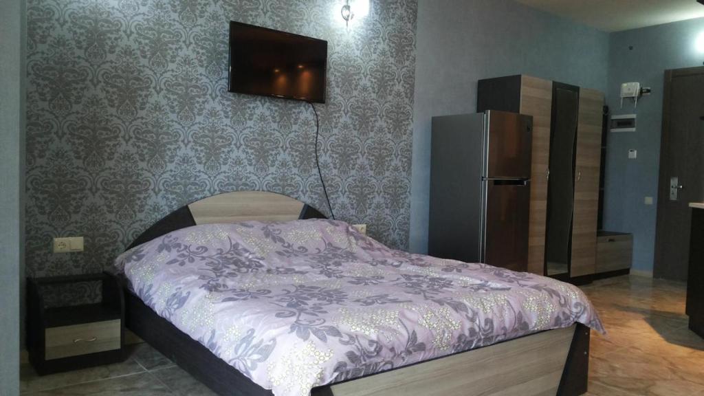 1 dormitorio con 1 cama con edredón morado y nevera en Kobaladze 4 Apartment en Batumi
