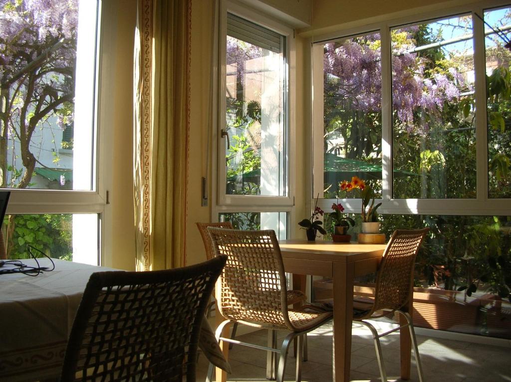 una sala da pranzo con tavolo, sedie e finestre di b&b undici a Cervia