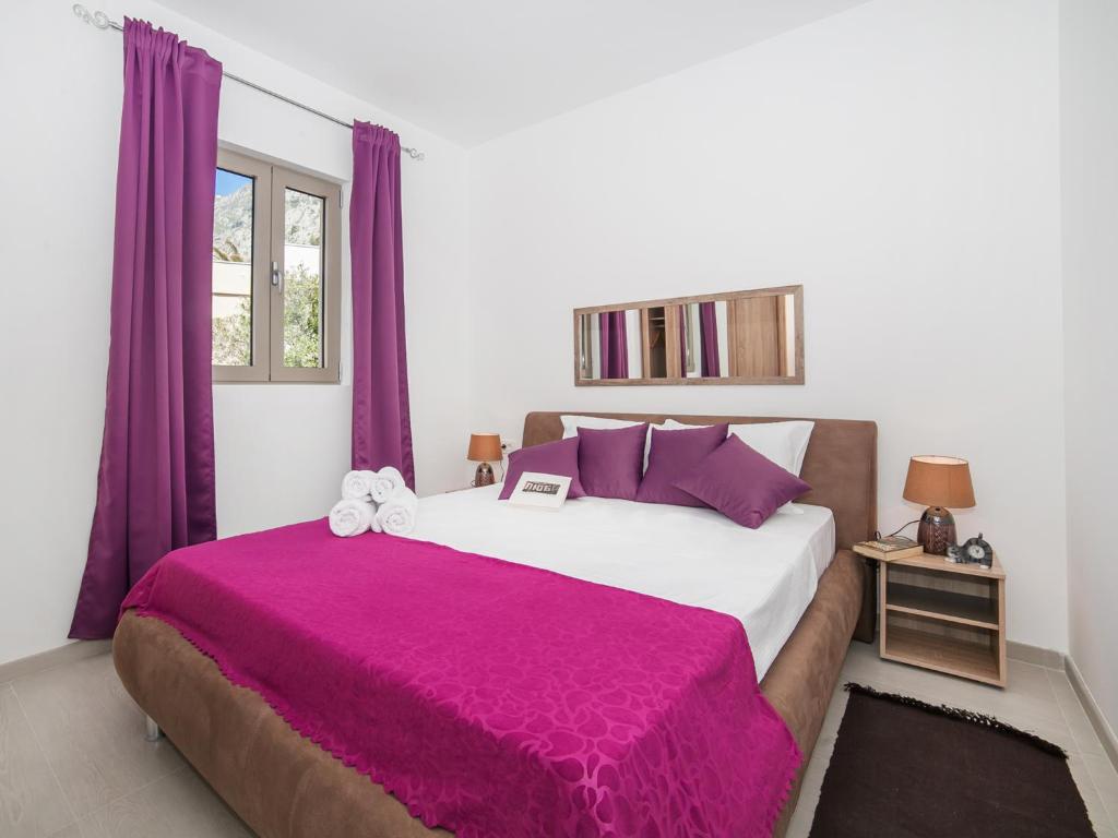 a bedroom with a large bed with purple curtains at Apartments Castello in Kotor