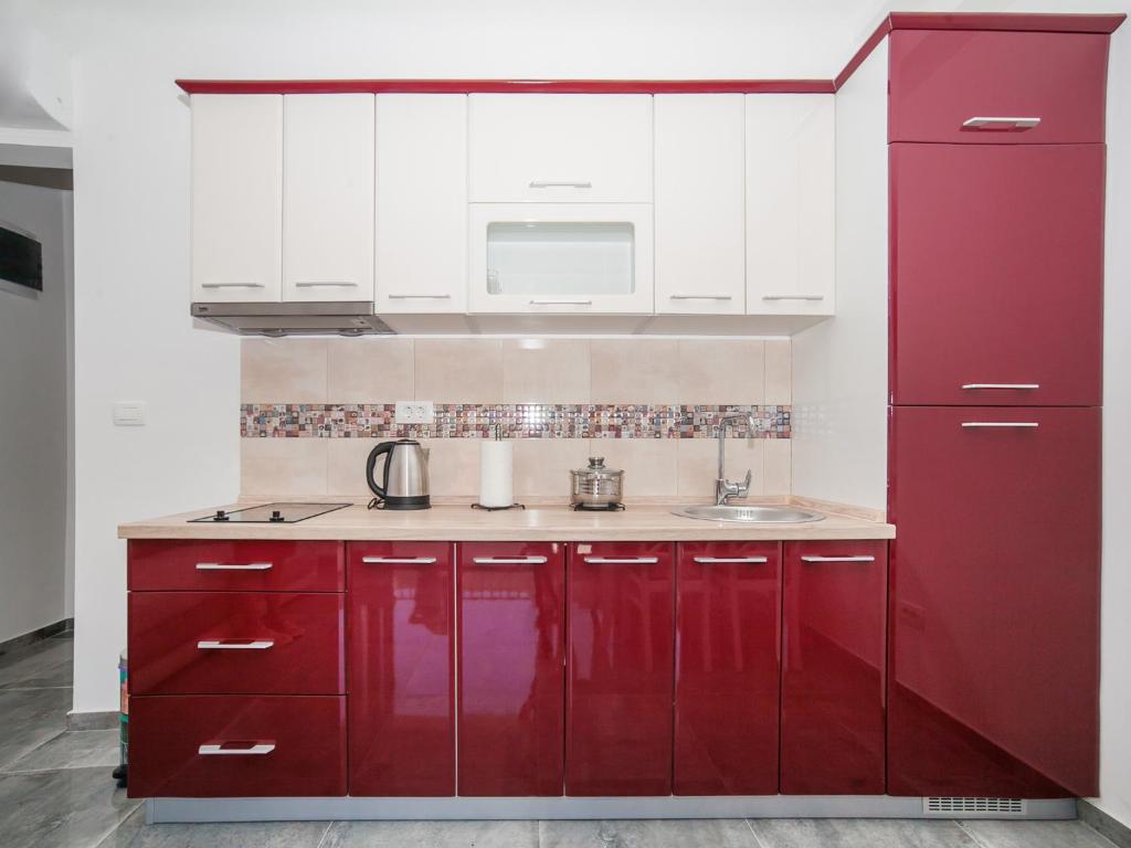 a red kitchen with white cabinets and a sink at Apartments Castello in Kotor
