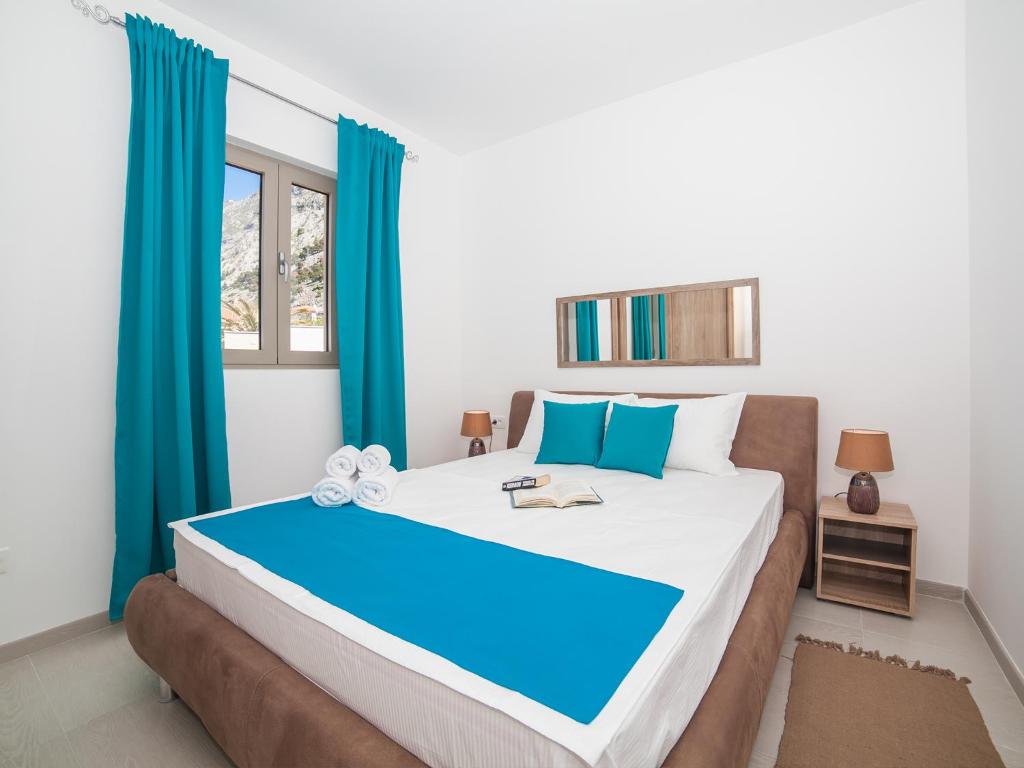 a bedroom with a large bed with blue curtains at Apartments Castello in Kotor
