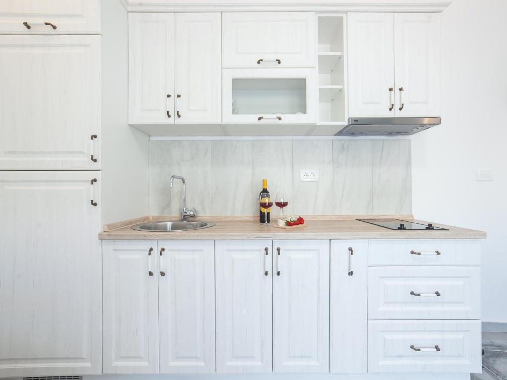 a white kitchen with white cabinets and a sink at Apartments Castello in Kotor
