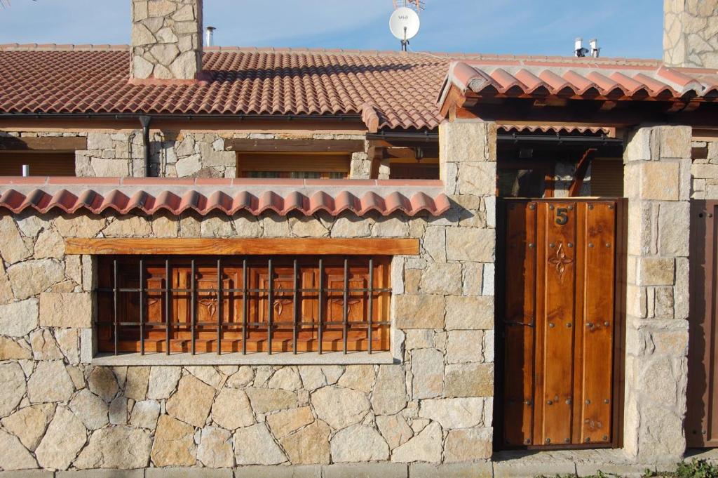 a stone building with two windows and a gate at Gredos Casa Rural Los Treboles in San Martín de la Vega del Alberche