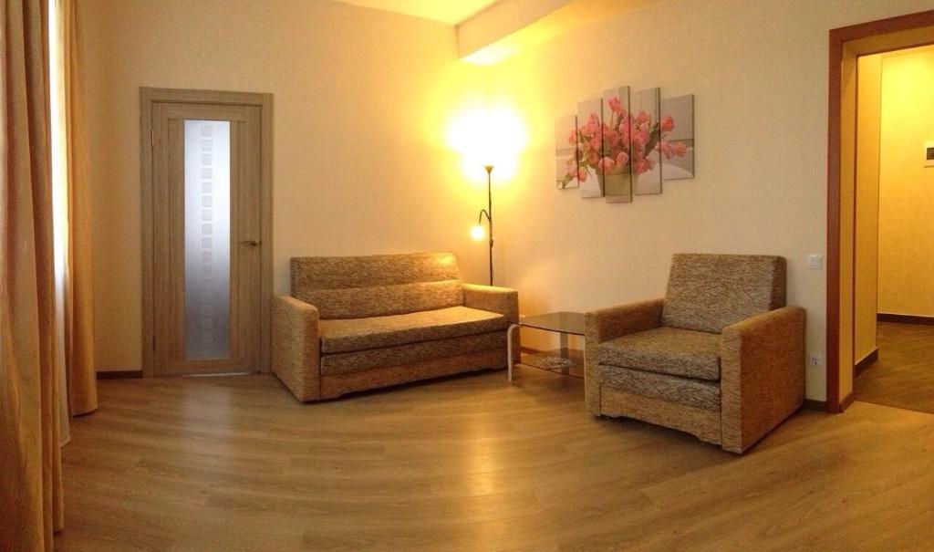 a living room with two chairs and a lamp at Apartament na Vielikoy in Velikiy Novgorod