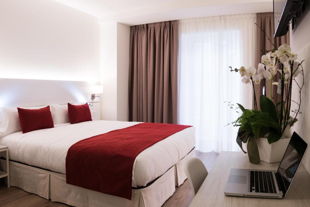 una habitación de hotel con una cama y un ordenador portátil en un escritorio en Hotel Pompaelo Plaza del Ayuntamiento & Spa, en Pamplona