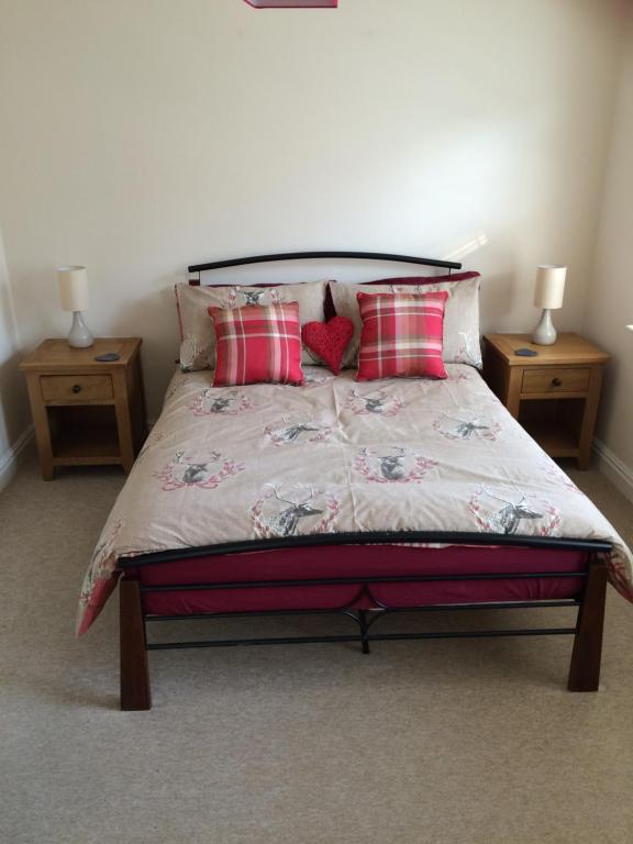 - une chambre avec un lit avec des oreillers rouges et 2 tables dans l'établissement The Custards, à Shanklin
