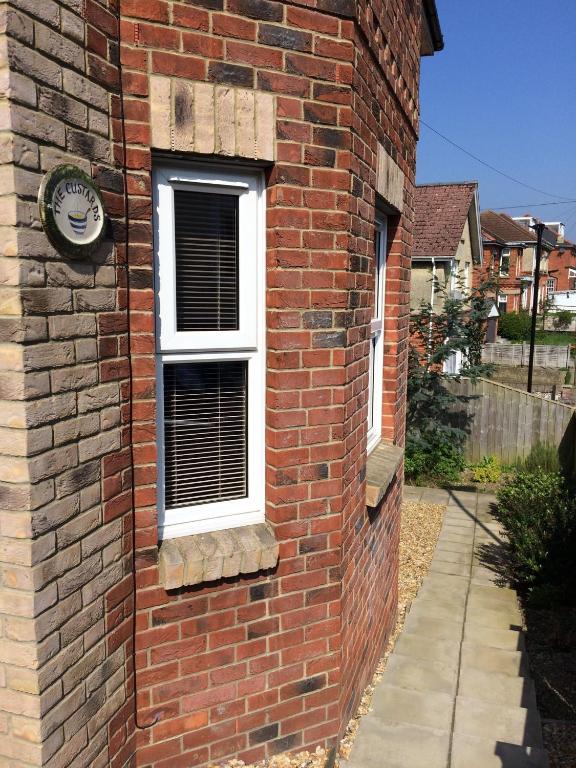 a brick building with a window and a clock on it at The Custards in Shanklin