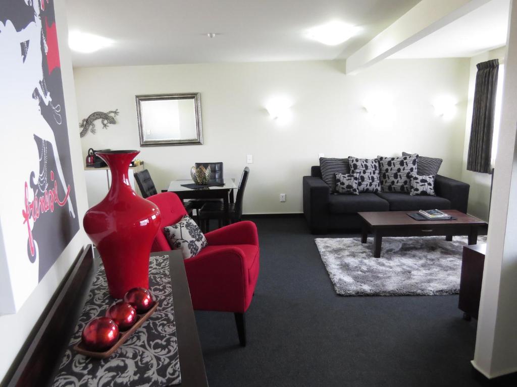 sala de estar con silla roja y sofá en Homestead Villa Motel, en Invercargill