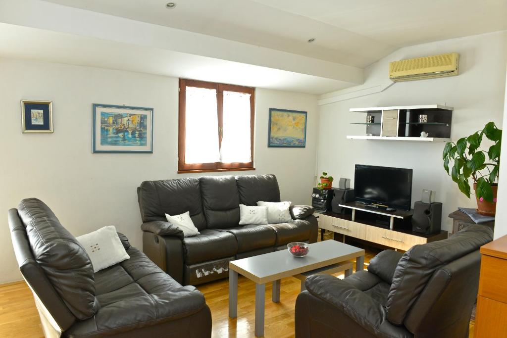 a living room with a leather couch and a tv at Apartment Juras in Opatija