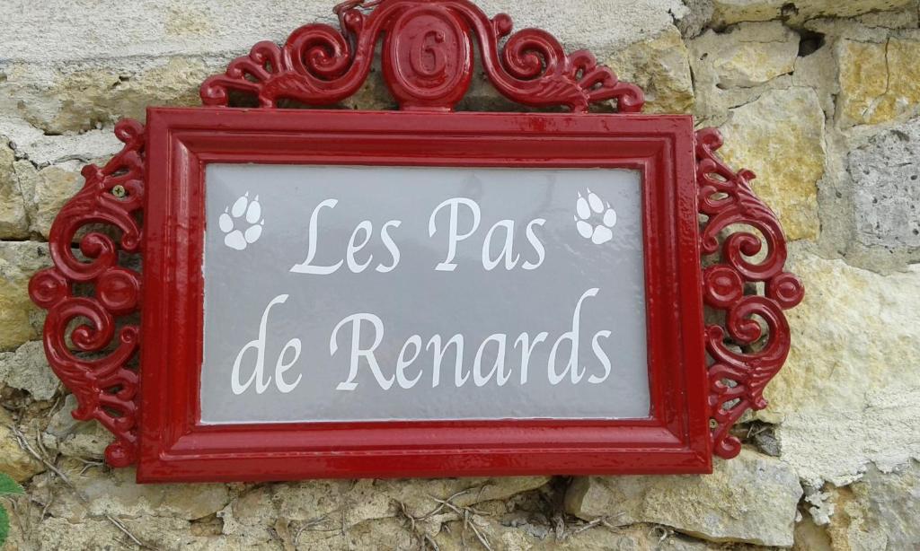 a sign in a red frame on a stone wall at Gîte Des Pas De Renards in Ruffec