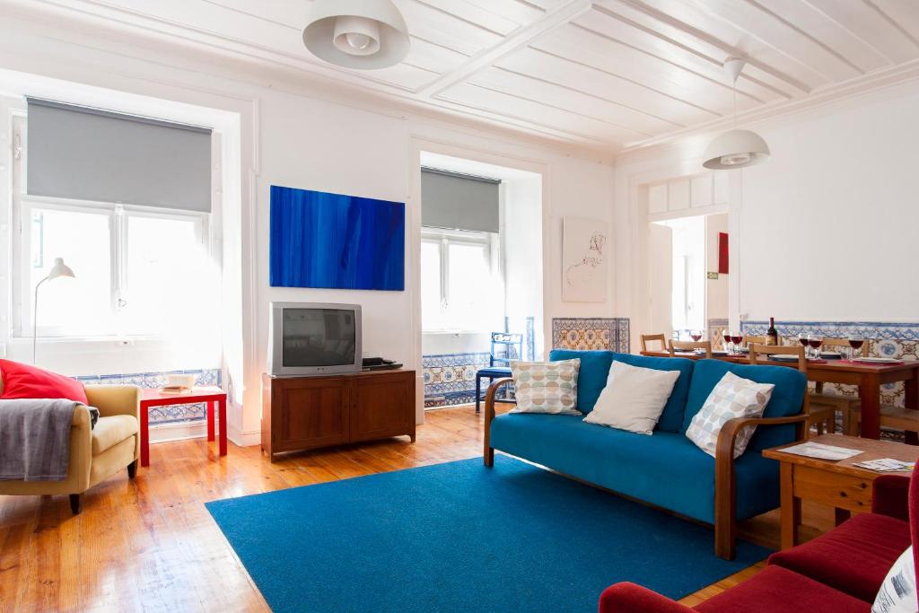 uma sala de estar com um sofá azul e uma televisão em ALTIDO Classic 3BR home with workspace in Chiado, 2mins from Baixa-Chiado subway em Lisboa