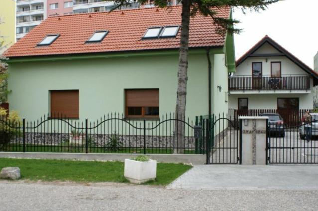 una casa blanca con una valla negra y un árbol en Vila Ria, en Bratislava