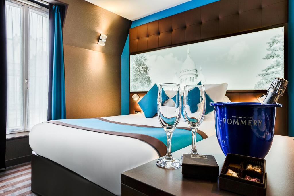 パリにあるベスト ウエスタン ヌーヴル オルレアンズ モンパルナスのベッド1台、テーブルにグラス2枚が備わる客室です。