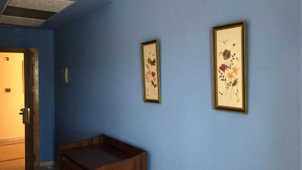 tres fotos en una pared azul con una caja de madera en Hotel La Atalaya, en Fuentidueña de Tajo