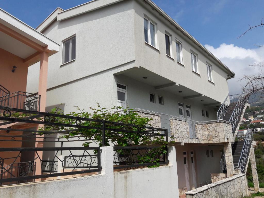 a large white building with a balcony and stairs at Apartments Vila Kurtagic in Dobra Voda