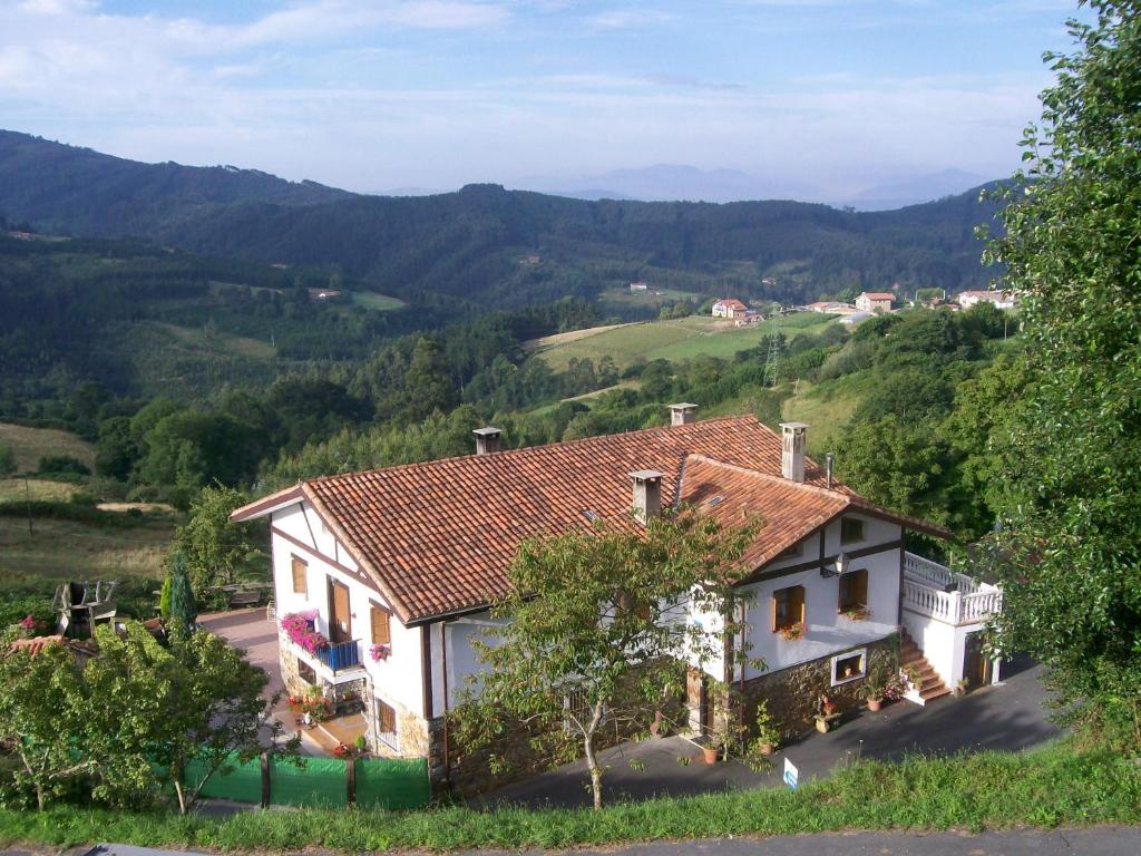 una casa en una colina con montañas en el fondo en Agroturismo Kasa Barri, en Bermeo