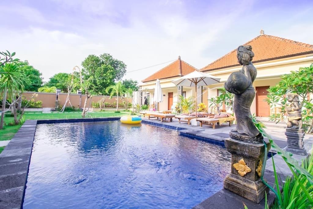 a swimming pool with a fountain in front of a house at Kutuh Manak Guest House in Uluwatu