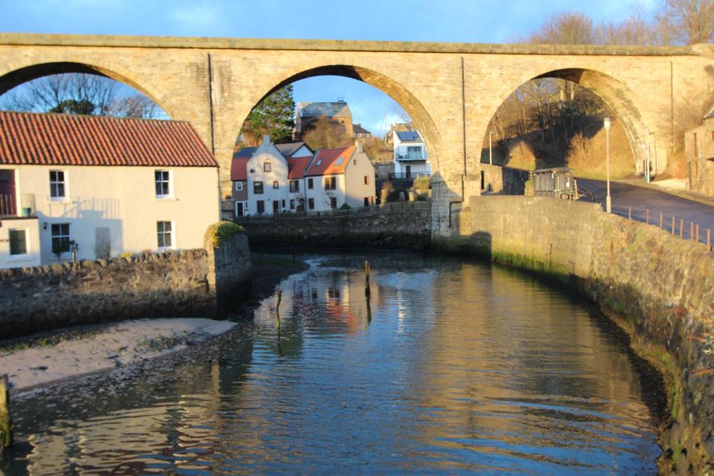 un puente sobre un río en una ciudad con edificios en Mill Cottage en Lower Largo