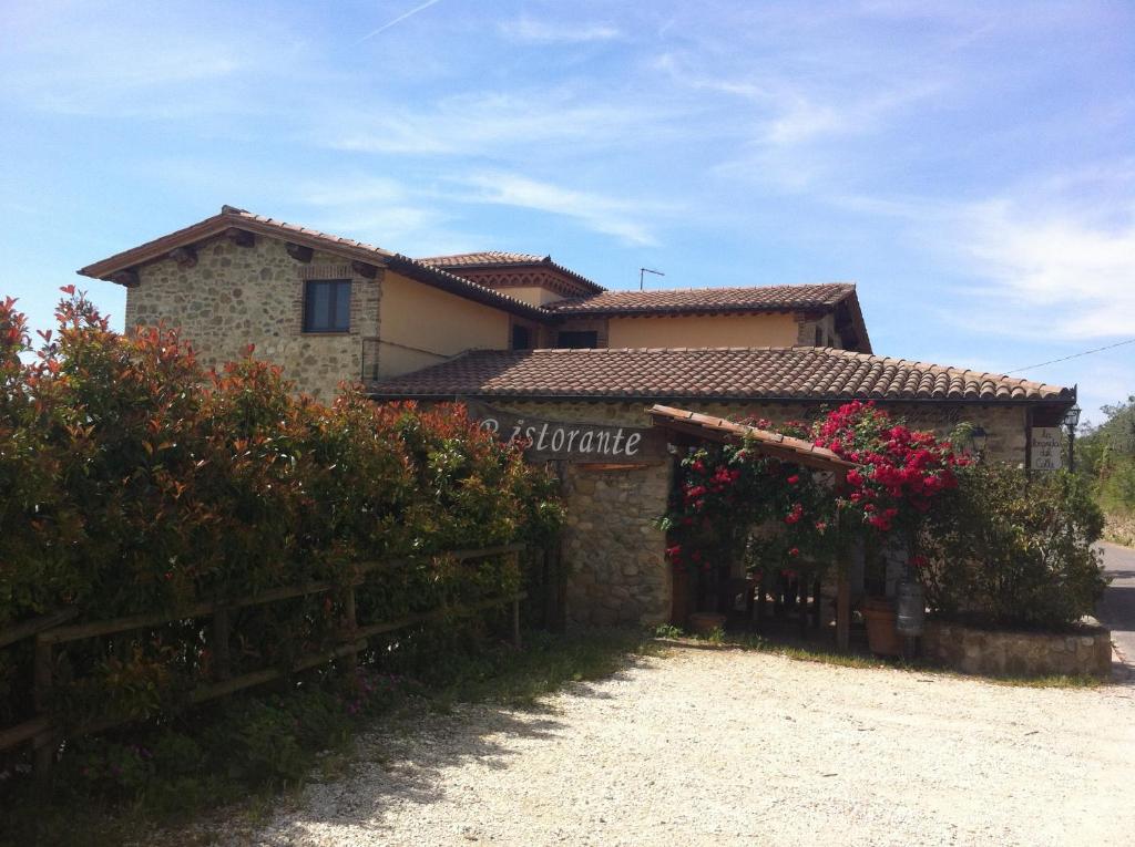 una casa con una valla y flores delante de ella en La Locanda Del Colle, en Canalicchio