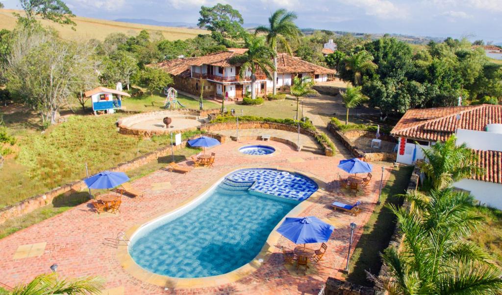 an aerial view of a swimming pool with umbrellas and a house at Hotel Buenosaires Barichara in Barichara