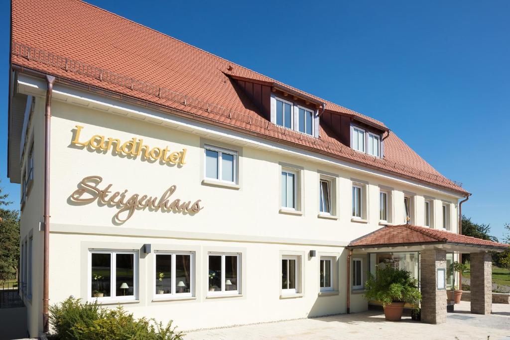 a large white building with a red roof at Landhotel Steigenhaus in Untermünkheim