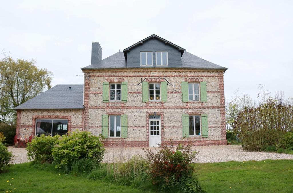 una antigua casa de ladrillo con persianas verdes en Chambres d'Hôtes " Le Clos des Colimaçons ", en Maniquerville